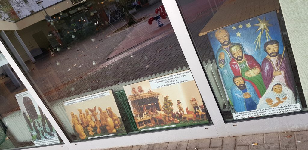 Vier Weihnachtskrippenfotos im Fenster des Begegnungszentrums Kinderhaus